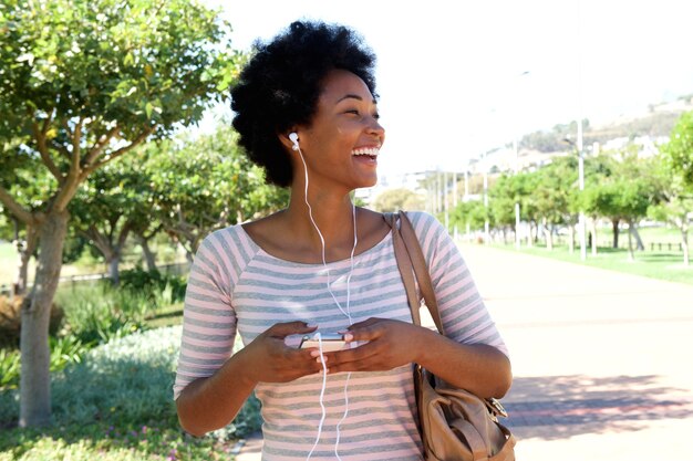 Smiling woman walking in park with headphones