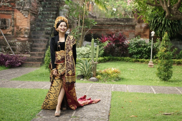 Smiling woman wearing balinese kebaya walking on the path