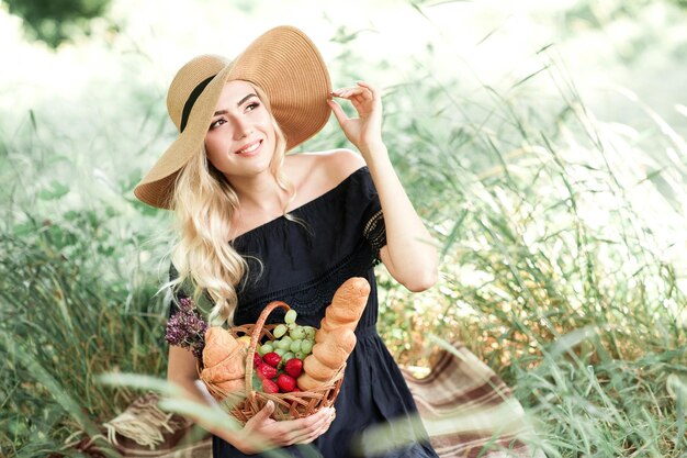 Photo smiling woman wearing hat holding basket of fruits looking away