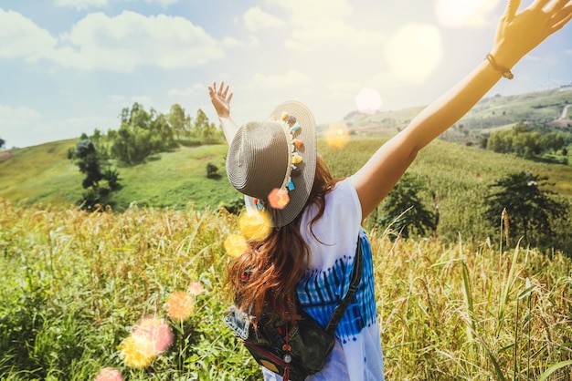 Smiling woman wearing hat standing on field against sky