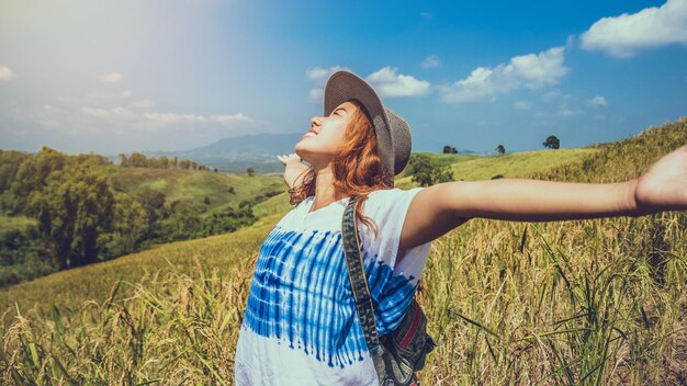 Smiling woman wearing hat standing on field against sky