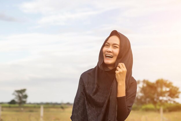 smiling woman wearing headscarf looking away against sky