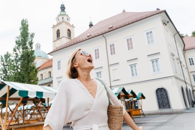 Smiling woman wearing stylish outfit walking on street of Ljubljana old town SloveniaTravel Europe