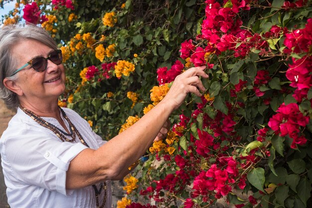 Foto donna sorridente con gli occhiali da sole che guarda le piante