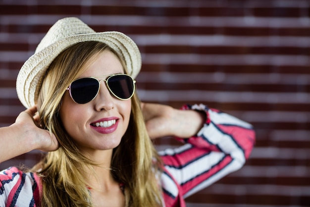 Smiling woman wearing sunglasses while stretching herself