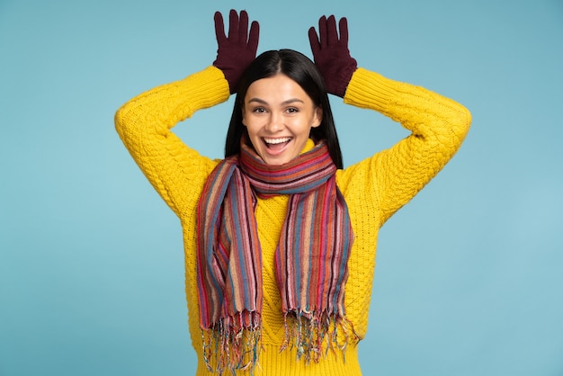 Foto donna sorridente che indossa maglione lavorato a maglia sciarpa e guanti che gesticolano e le tengono le mani