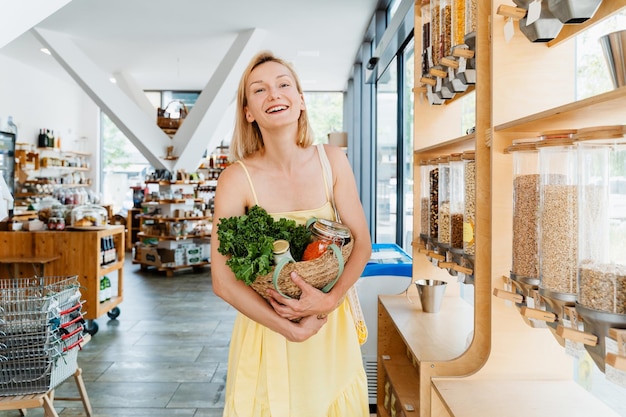 Smiling woman with basket of organic products in sustainable plastic free store