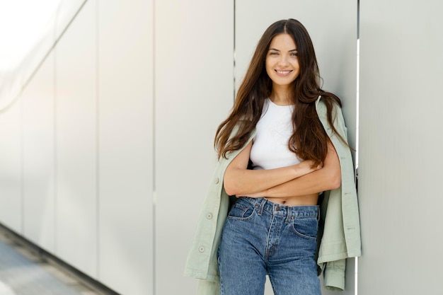 Smiling woman with beautiful long hair wearing trendy casual clothing looking at camera on street