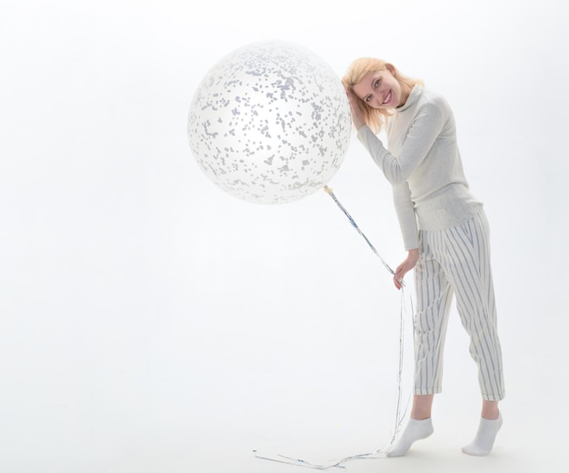 Smiling woman with big balloon. Party mood. Celebration concept. Big white balloon. Woman holds flying balloon. Advertising concept. Birthday party. Isolated on white background. Copy space.