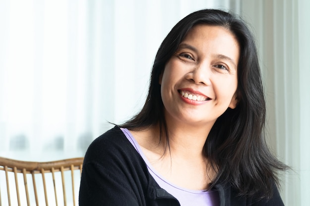 Photo smiling woman with black long hair sitting indoor