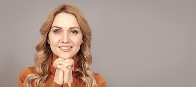 Smiling woman with blond curly hair hold hands with hope in\
look copy space face portrait woman portrait isolated header banner\
with copy space