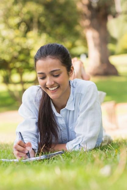 Smiling woman with book and pen in park