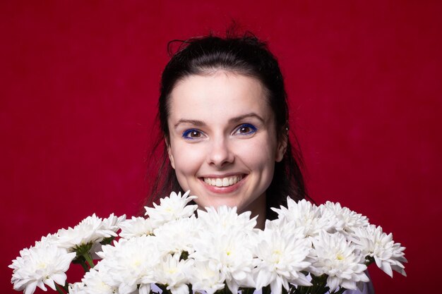 smiling woman with bouquet of white flowers red background