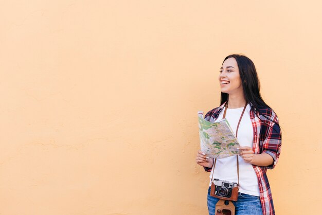 Foto donna sorridente con la macchina fotografica intorno alla sua mappa della tenuta del collo