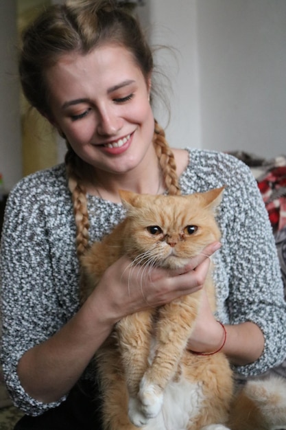 家に座っている猫を持った笑顔の女性