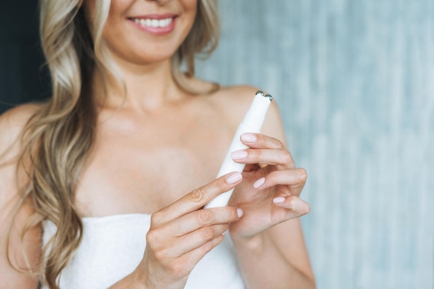 Smiling woman with clean fresh face and hands doing fasial massage with microcurrent facial massager