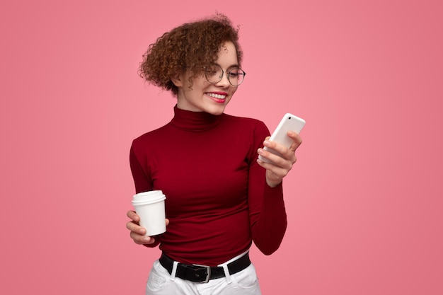 Smiling woman with coffee using smartphone