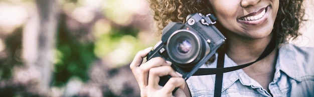 Smiling woman with digital camera at park