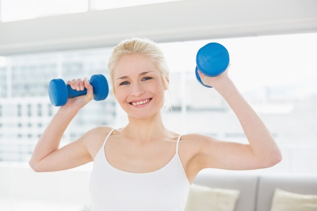 Smiling woman with dumbbells at fitness studio