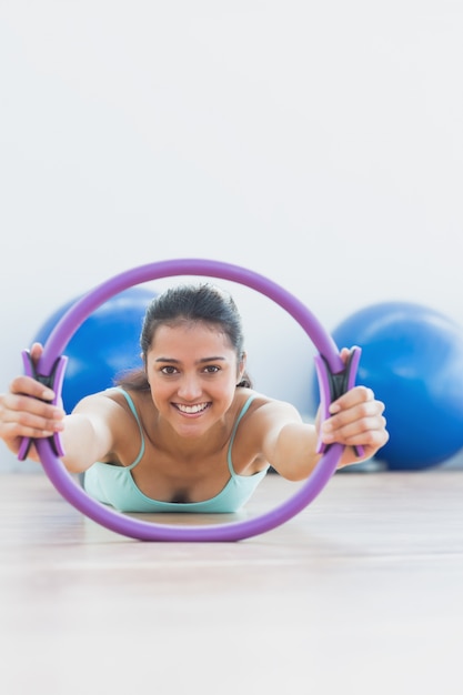 Foto donna sorridente con l'esercitazione dell'anello nello studio di forma fisica