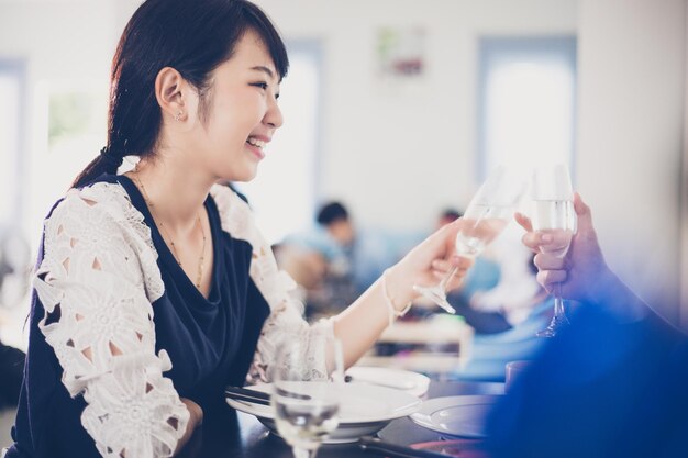 写真 レストランで友人と一緒にワイングラスを乾杯する笑顔の女性