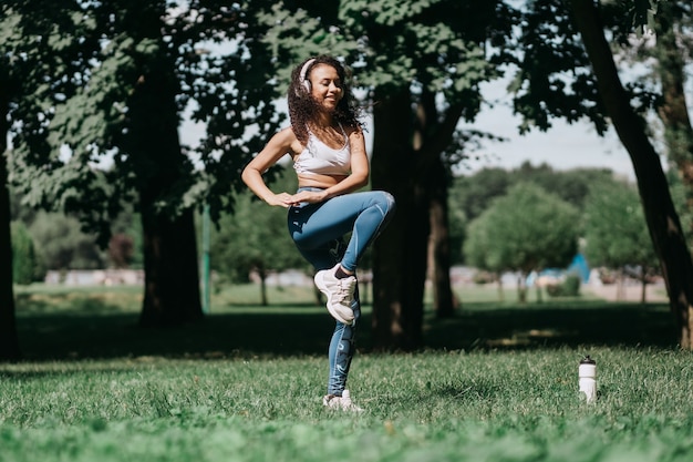 Donna sorridente con le cuffie che esegue esercizi di fitness in a