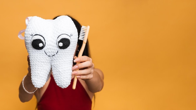 A smiling woman with healthy teeth holds a toothbrush in her hands A young beautiful girl on a bright isolated background Oral hygiene A place for your text