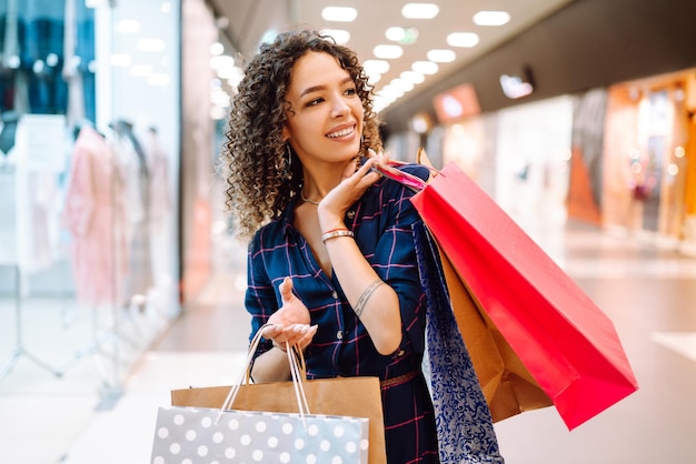 Smiling woman with shopping bags enjoying shopping in mallYoung woman with packages after shopping