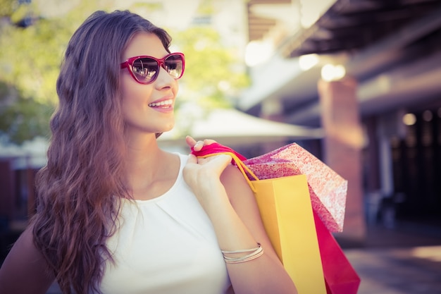 Smiling woman with shopping bags wearing sunglasses