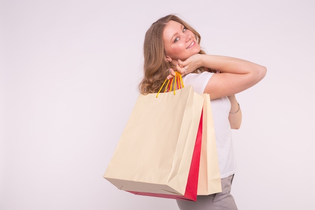 Smiling woman with shopping bags on white surface
