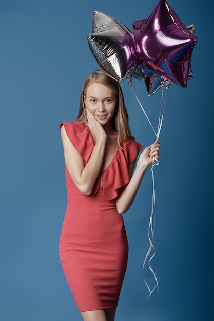 Smiling woman with star balloons on blue wall