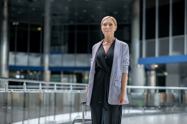 Smiling woman with suitcase walking in airport