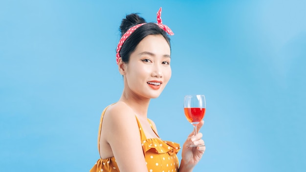 Smiling woman in yellow dress with glass of sparkling wine over blue background