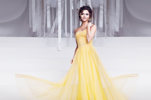 Smiling woman in yellow evening dress and with beautiful hairstyle