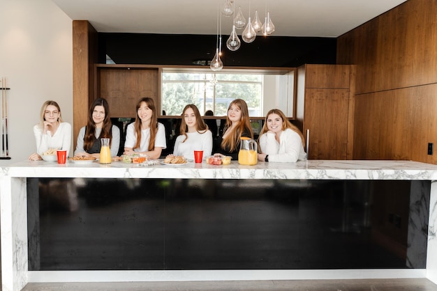 Smiling women colleagues standing at kitchen at home and looking at camera while posing during party Happy people concept