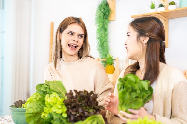 Smiling women preparing fresh healthy salad vegetables woman sitting at pantry in a beautiful interior kitchen The clean diet food from local products and ingredients Market fresh