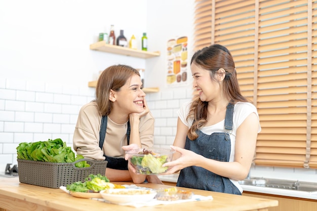 Smiling women preparing fresh healthy salad vegetables woman sitting at pantry in a beautiful interior kitchen The clean diet food from local products and ingredients Market fresh