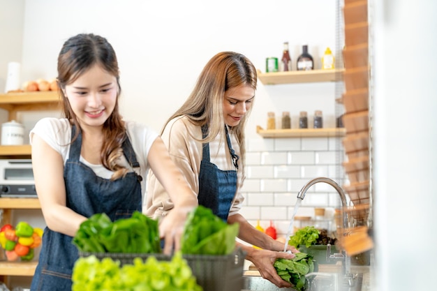 Smiling women preparing fresh healthy salad vegetables woman standing at pantry in a beautiful interior kitchen The clean diet food from local products and ingredients Market fresh