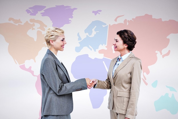 Photo smiling women shaking hands against grey background