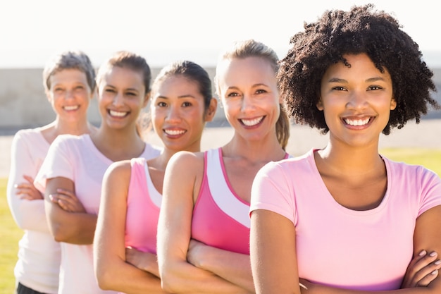 Foto donne sorridenti che indossano rosa per il cancro al seno con le braccia incrociate