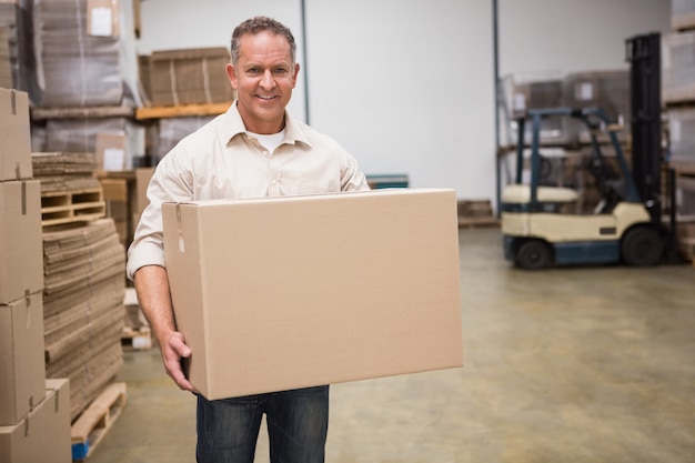 Smiling worker carrying a box