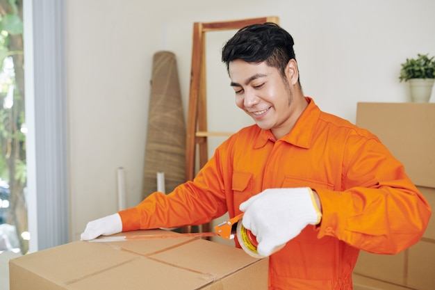 Smiling worker sealing boxes