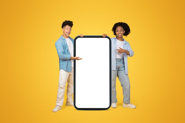 Smiling young african american guy and woman in casual point at huge smartphone