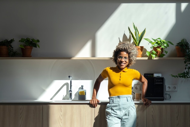 Smiling young african american woman with curly hair in front of office kitchen Copy space