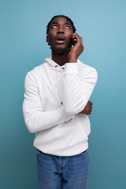 Smiling young african guy in a white sweatshirt chatting on the phone