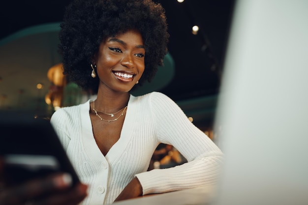 カフェでラップトップで座っている笑顔の若いアフリカ人女性