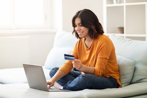 Photo smiling young arab woman making online payments with laptop and credit card