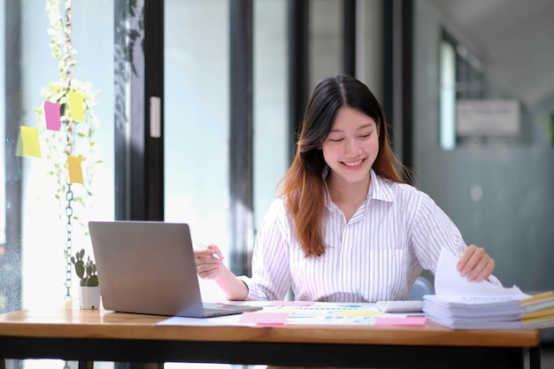 Smiling Young Asian Business women working with calculator business document and laptop computer notebookfinancial inspector and secretary making reportInternal Revenue Service checking document