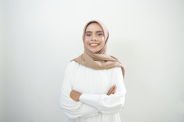 Улыбающаяся молодая азиатская мусульманка чувствует себя уверенно и радостно изолированной на белом фоне