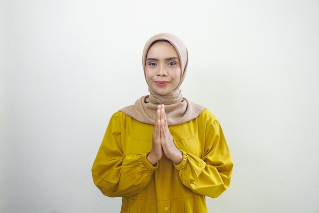 Smiling young Asian Muslim woman gesturing Eid Mubarak greeting isolated over white background